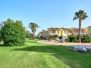 une grande cour avec des palmiers et des maisons dans l'établissement BQ Alcudia Sun Village, à Playa de Muro