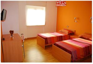 2 camas en una habitación con paredes de color naranja y ventana en Il Falco e Il Gabbiano, en Corigliano Calabro 94 fotos más