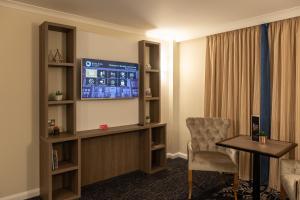 um quarto com uma televisão, uma mesa e uma cadeira em Burleigh Court Hotel and Leisure em Loughborough