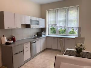 a kitchen with white cabinets and a table and two windows at Apartament "Marka" in Piła