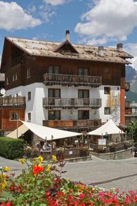 un gran edificio con mesas y sombrillas delante en Assietta, en Sauze dʼOulx