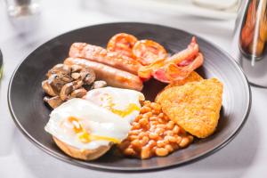 a plate of food with eggs, sausage, beans and bacon at Burleigh Court Hotel and Leisure in Loughborough