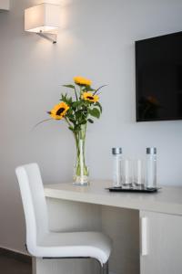 eine Vase mit Blumen auf einem Tisch mit einem weißen Stuhl in der Unterkunft Aparthotel Esquinzo Y Monte Del Mar in Playa Jandia