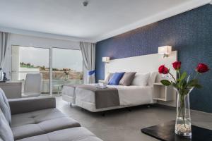 - une chambre avec un lit et un vase avec des roses rouges dans l'établissement Aparthotel Esquinzo Y Monte Del Mar, à Playa Jandía