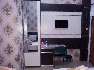 een kleine kamer met een bed, een wastafel en een bureau bij Trivadoh Syariah Hotel in Padangpanjang