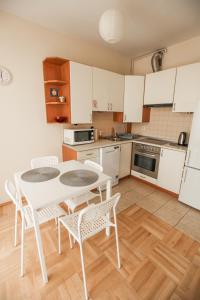 ワルシャワにあるGreen Kabaty Apartment 2の白いキャビネット、テーブルと椅子付きのキッチンが備わります。