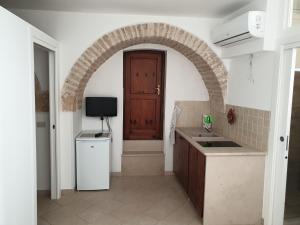 uma cozinha com um arco com um lavatório e um frigorífico em Nonna Livia em Alberobello