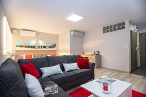 soggiorno con divano grigio e cuscini rossi di Apartamenty ELITMAT a Mińsk Mazowiecki