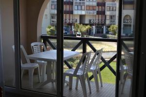 a table and chairs on a balcony with a window at Appartement à 50m de la plage in Soorts-Hossegor