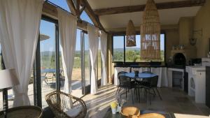 a kitchen and dining room with large windows and a table at Le Clos d'Estellan - Piscine chauffée in Bonnieux