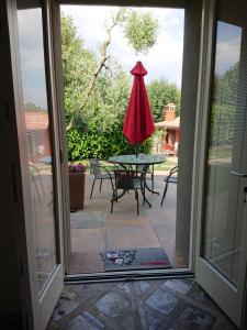 una puerta abierta a un patio con mesa y sombrilla en Il carpino bianco, en Puegnago sul Garda