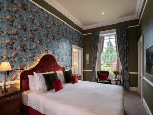 a bedroom with a large bed with a floral wallpaper at SCHLOSS Roxburghe, part of Destination by Hyatt in Kelso