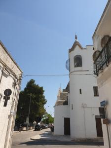 um edifício branco com uma torre de relógio numa rua em Nonna Livia em Alberobello