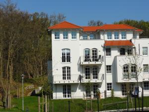 バーベにある3 Zimmer Ferienwohnung Haus Meeresblick mit Meerblick A005 mit Südterrasse und Strandkorbのオレンジ色の屋根の白い大きな建物