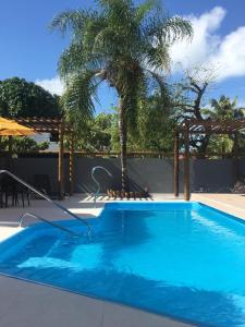 una gran piscina azul con una palmera en Pousada Aconchego, en Praia do Frances