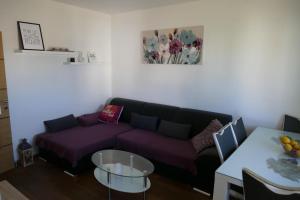 uma sala de estar com um sofá roxo e uma mesa em Heidi em Podstrana