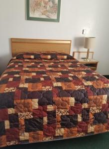 a bed with a quilt on it in a room at Oregon Trail Motel and Restaurant in Baker City