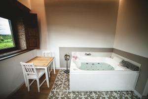 una vasca da bagno in una stanza con tavolo e sedia di Posada La Corralada a Pámanes