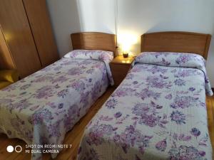 two beds in a room with two lamps on at Hostal Bayón in León