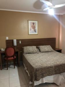 ein Schlafzimmer mit einem Bett und einem Schreibtisch mit Stuhl in der Unterkunft Victor Plaza Formiga in Formiga