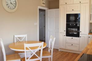 cocina con mesa y reloj en la pared en Atlantic Rose Cottage, en Doolin