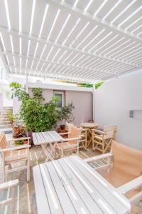 a patio with tables and chairs and a white ceiling at Flora in Tinos Town
