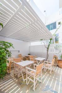 un patio con mesas y sillas bajo una pérgola blanca en Flora, en Tinos
