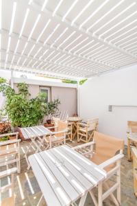 a patio with chairs and tables and a white ceiling at Flora in Tinos
