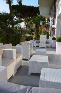 een groep witte stoelen en tafels op een patio bij Hotel Mirage in Milano Marittima