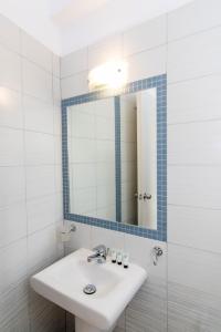 Baño blanco con lavabo y espejo en Flora, en Tinos