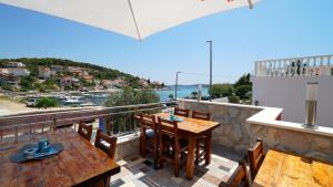 a balcony with tables and chairs and a view of the water at Guest House Sandra in Tisno