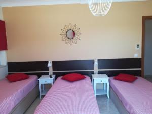 two beds in a room with pink sheets and red pillows at My Guest House in Portimão