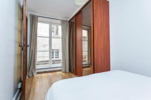 um quarto com uma cama e uma janela grande em Apartment Saint Jacques Notre Dame de Paris em Paris