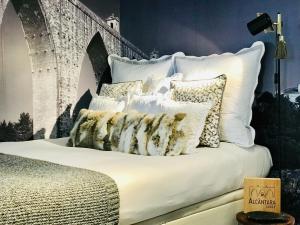 uma cama com almofadas brancas em cima em Alcântara Lodge em Lisboa