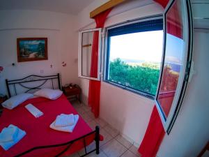 a bedroom with a red bed and a large window at The Captain in Elafonisos
