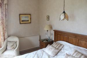 a bedroom with a bed and a chair and a lamp at The Grange in East Barkwith