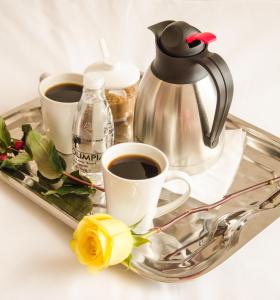 ein Tablett mit zwei Tassen Kaffee und einem Wasserkocher in der Unterkunft HOTEL OLIMPIA in Duitama