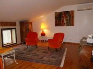 a living room with two red chairs and a rug at Le Moulinage in Saint-Thomé