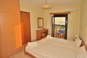 a bedroom with a white bed and a balcony at Xenios Zeus Apartments in Kissamos