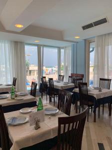 Un comedor con mesas y sillas y ventanas. en Hotel Mercedes, en Misano Adriatico