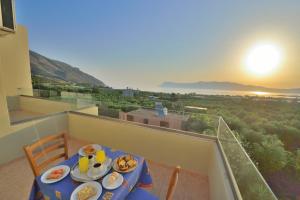 a table with plates of food on a balcony at Xenios Zeus Apartments in Kissamos