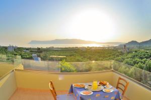a table with plates of food on a balcony at Xenios Zeus Apartments in Kissamos