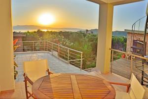 a balcony with a table and a view of the sunset at Xenios Zeus Apartments in Kissamos