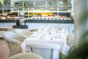 a table with white tables and chairs in a restaurant at Grupotel Club Menorca in Son Xoriguer