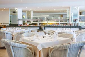 a restaurant with white tables and chairs and a counter at Grupotel Club Menorca in Son Xoriguer