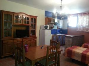 eine Küche mit einem Tisch und eine Küche mit einem Kühlschrank in der Unterkunft Pensión y apartamentos El Taxi in Casabermeja