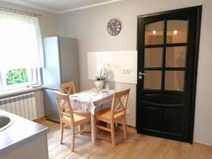 une cuisine avec une table et des chaises ainsi qu'une porte noire dans l'établissement Leśny Apartament, à Szczytno