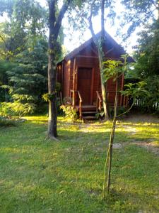 a log cabin in the middle of a yard with trees at Cabaña Las Nubes in Río Ceballos