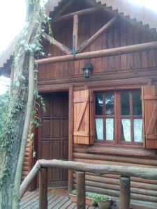 a wooden cabin with a wooden door and windows at Cabaña Las Nubes in Río Ceballos