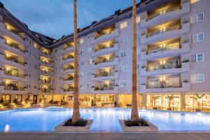 a hotel pool with two palm trees in front of it at AQUA Hotel Montagut Suites 4*Sup in Santa Susanna